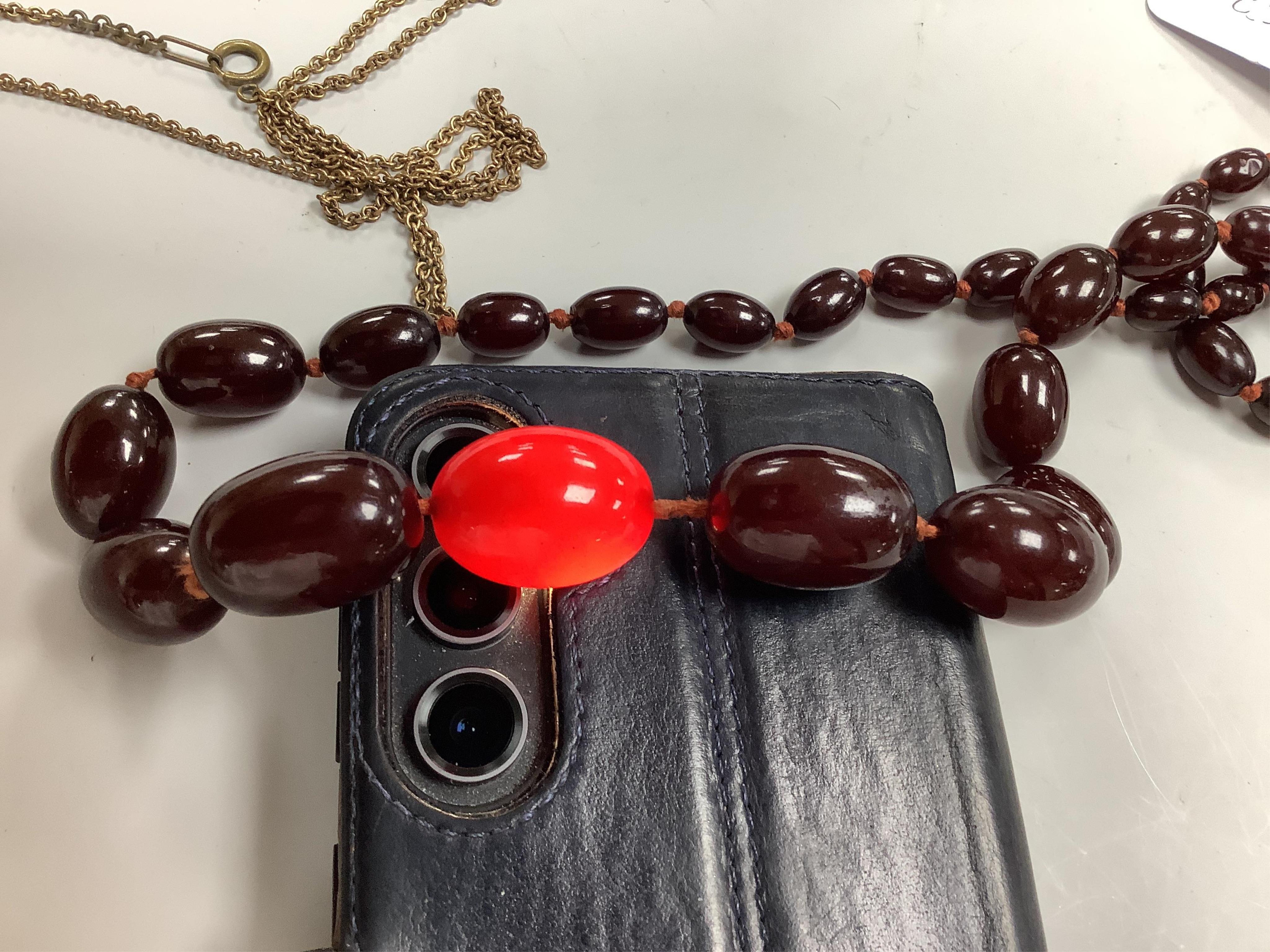 A cherry bakelite 'amber' necklace and pendant, comprising: a necklace composed of cherry-coloured bakelite beads measuring approximately 10 - 26mm, length 90cm, gross weight 72 grams; and a drop-shaped pendant, length 5